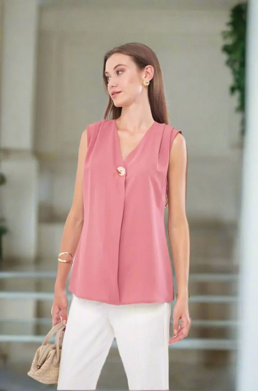 A woman smiling while standing on a staircase, wearing a pink sleeveless top with gold buttons